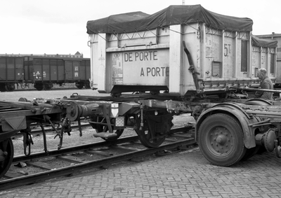 837843 Afbeelding van het overzetten van een autolaadkist van vrachtwagen naar spoor op het terrein van Van Gend & Loos ...